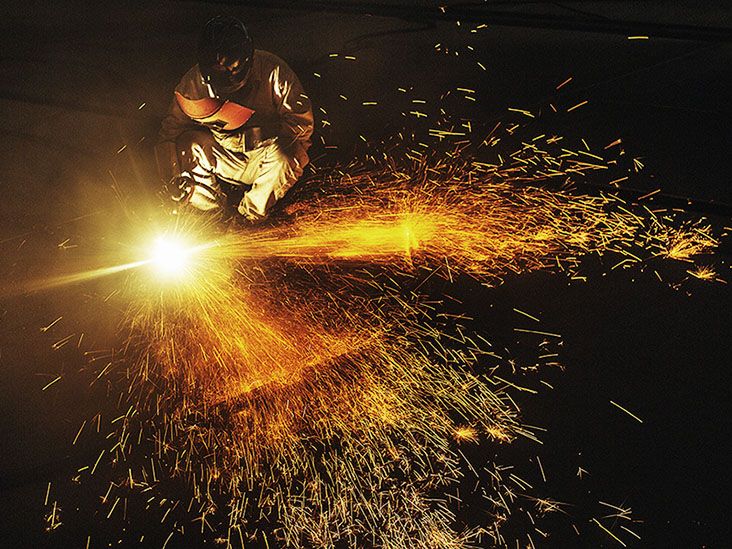 Welders working on cutting metal as sparks fly