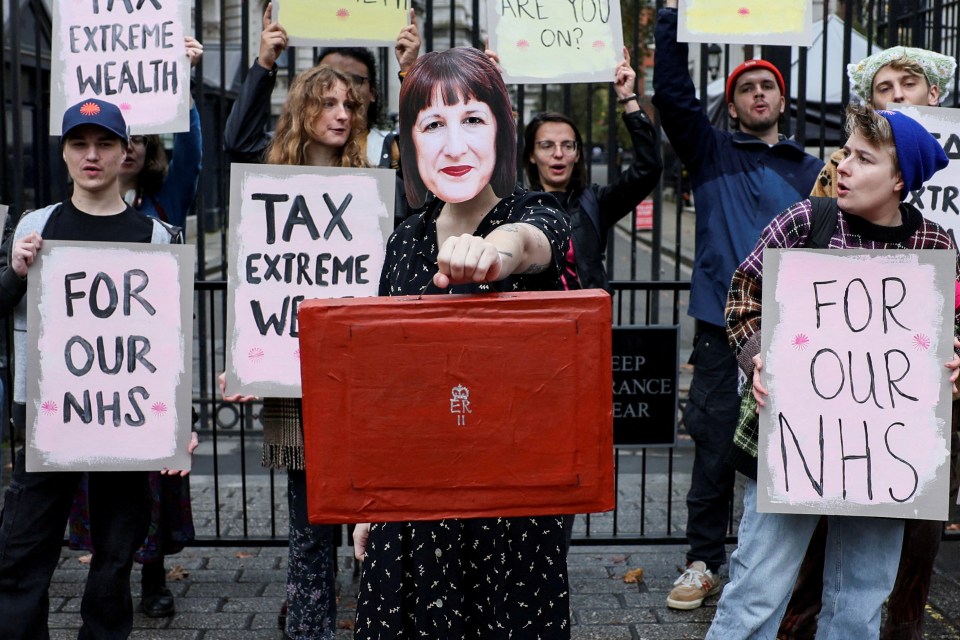 Demonstrator holds a mock red Budget box in protest at Downing Street