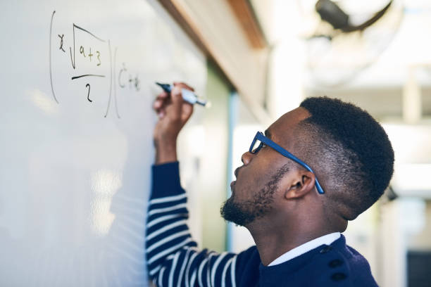 Cropped shot of a young man writing on a whiteboard in a classroom