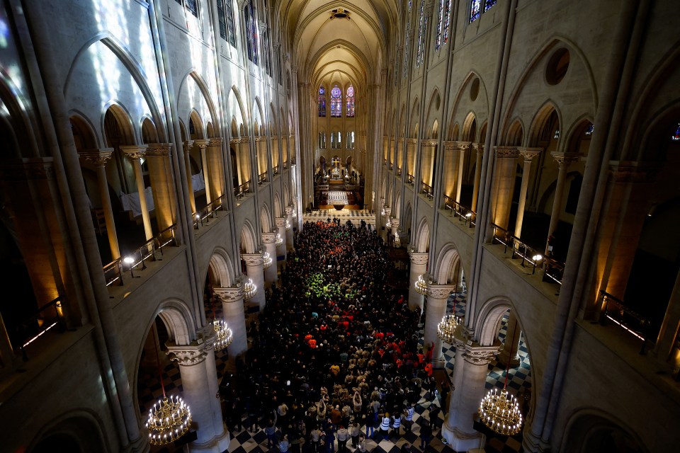 Attendees including workers of reconstruction of Notre-Dame de Paris cathedral gather during a speech by French President Emmanuel Macron