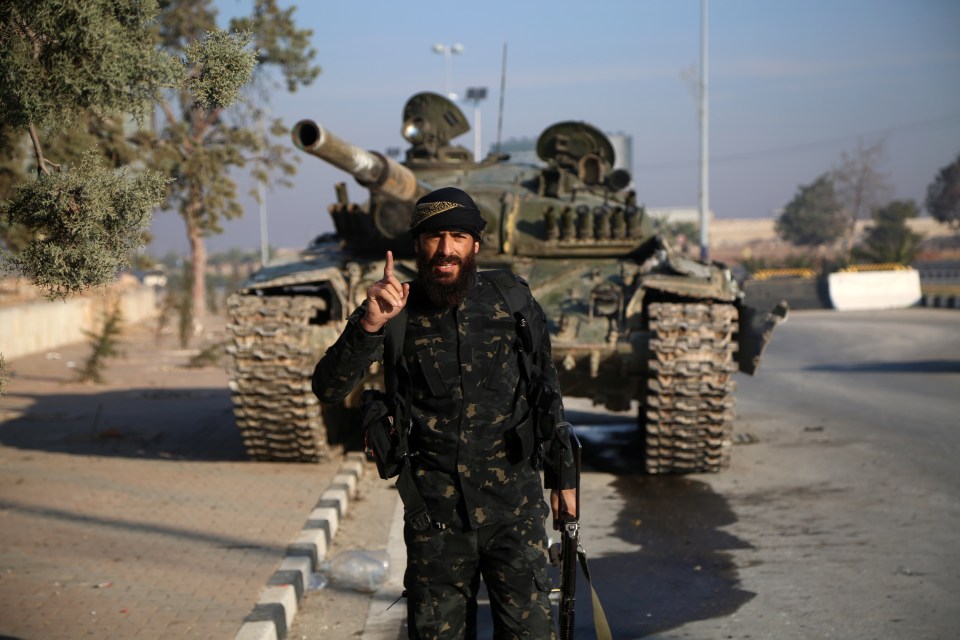 An armed man in front of a tank after rebel forces took control of the city