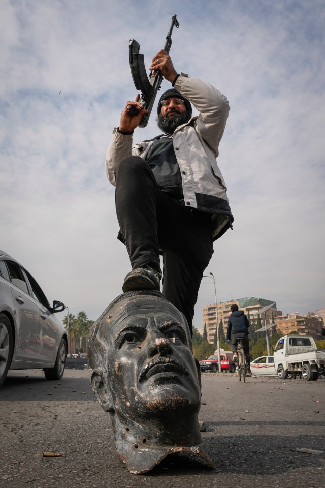 An opposition fighter steps on a bust of late Syrian President Hafez Assad in Damascus