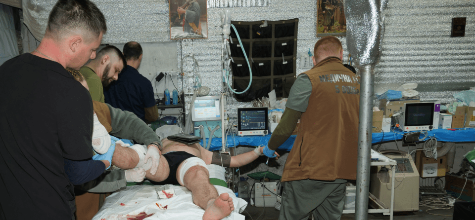 Several medics treat an injured Ukrainian soldier who has suffered injuries to his legs and hand