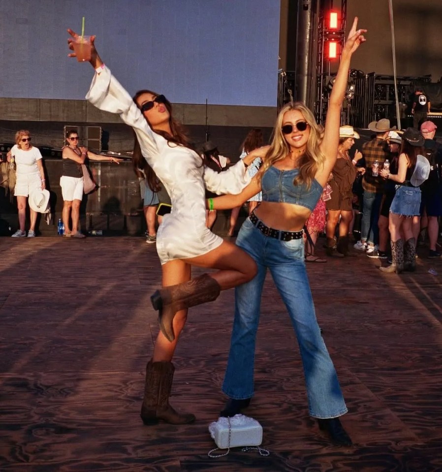 Two women in cowboy boots posing at a music festival.