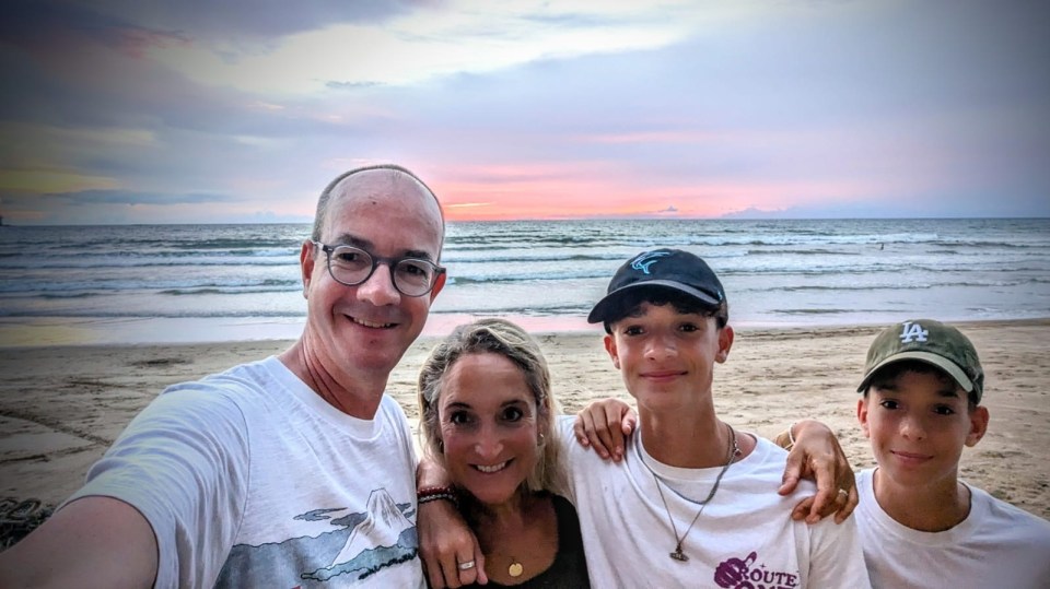 Family selfie on a beach at sunset.