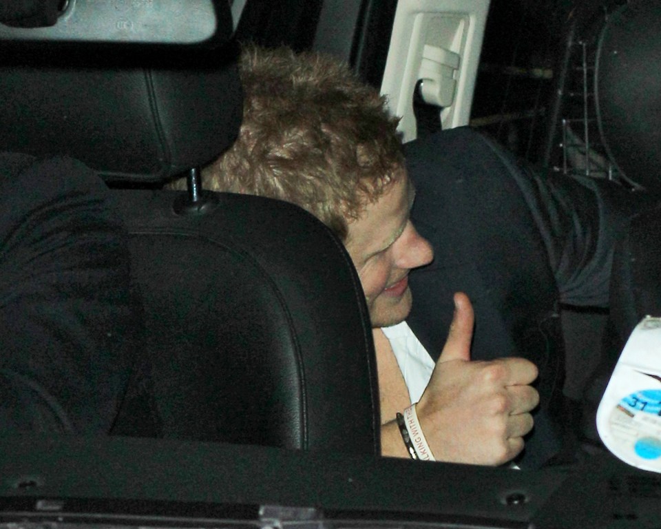 Prince Harry giving a thumbs up from inside a car.