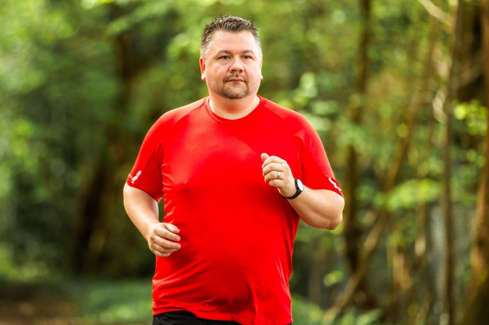 A man jogging through a sunlit forest.