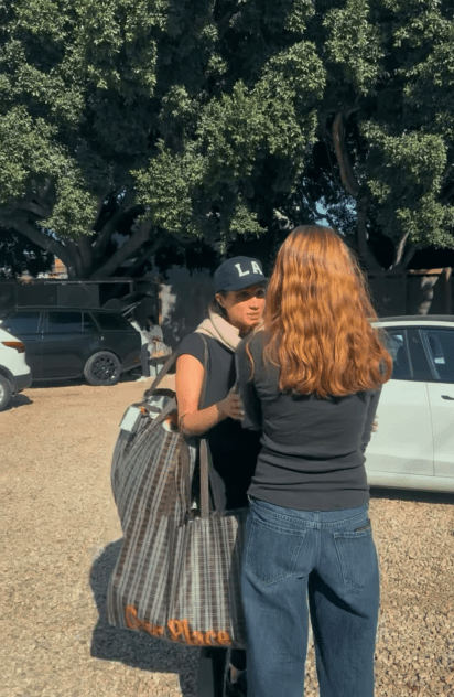 Two women talking near parked cars.