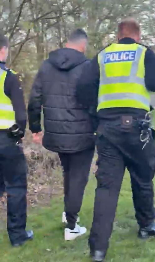 A man in custody escorted by two police officers.